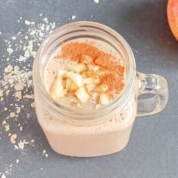 apple oatmeal breakfast smoothie in a mug placed on a black