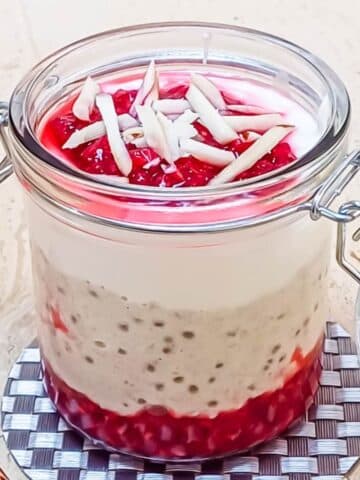 raspberry overnight oats in a jar placed on the coaster.