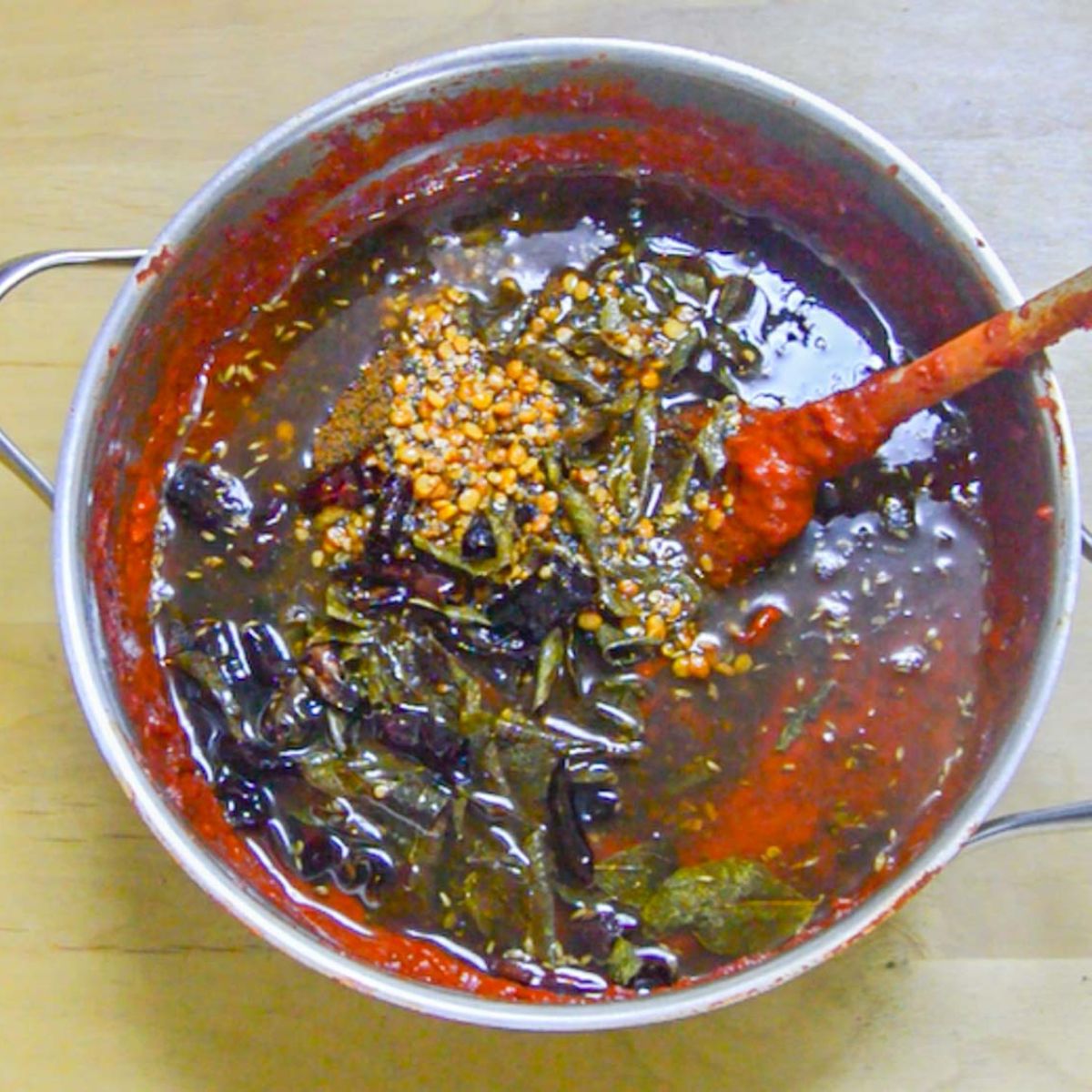 A pot of spicy tomato chutney with tempered spices on the top.