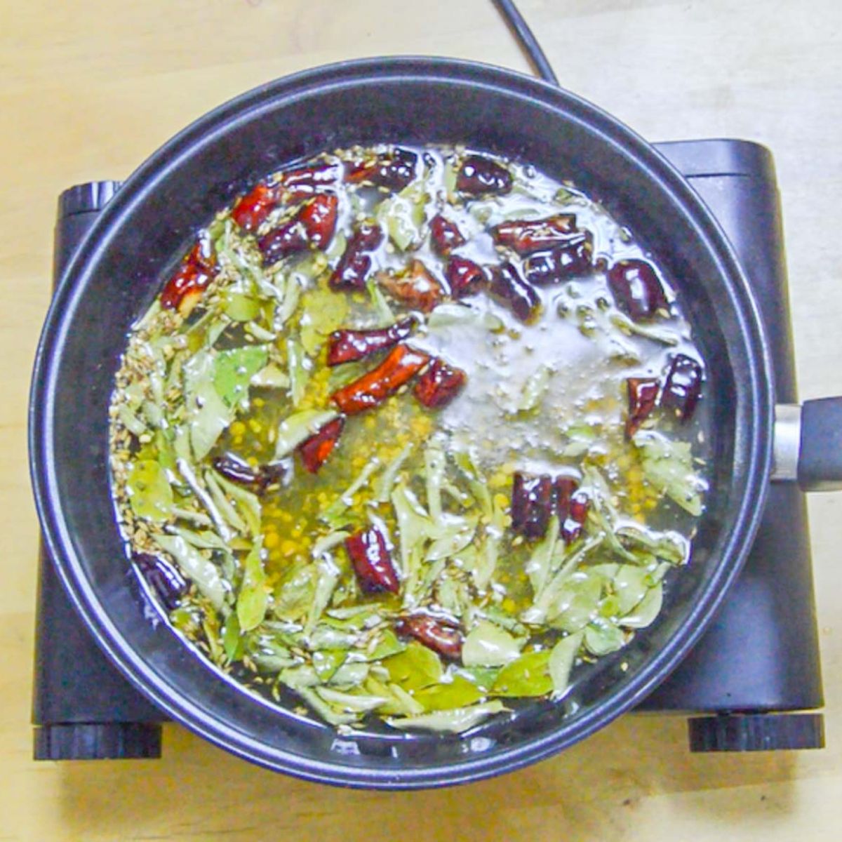 tempering spices in a black pan.