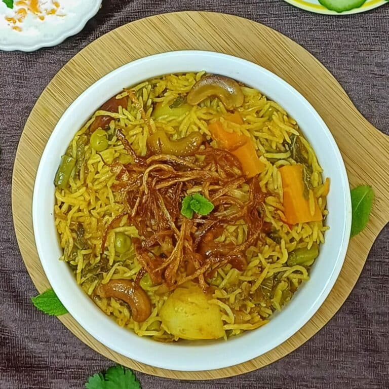 white pot of veggie biryani placed on the wooden board along with a bowl of yogurt and a plate of cucumber slices.