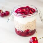 cherry overnight oats in a glass jar placed on the marble with fresh cherries on the side.