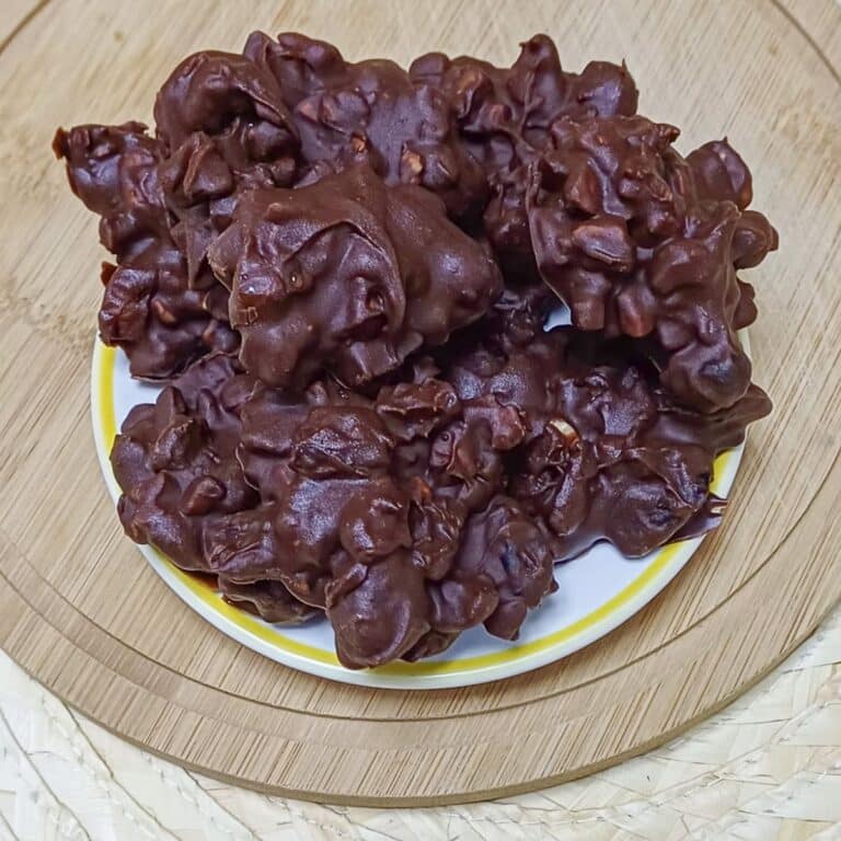 nut and fruit chocolate clusters placed on a plate on wooden board.