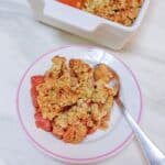 baked apple strawberry crisp in a white plate placed on marble