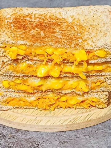 stack of carrot corn cheese sandwich on wooden board placed on a tile.