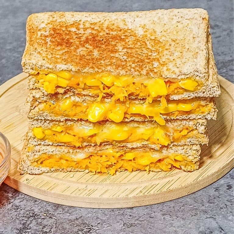 stack of carrot corn cheese sandwich on wooden board placed on a tile.