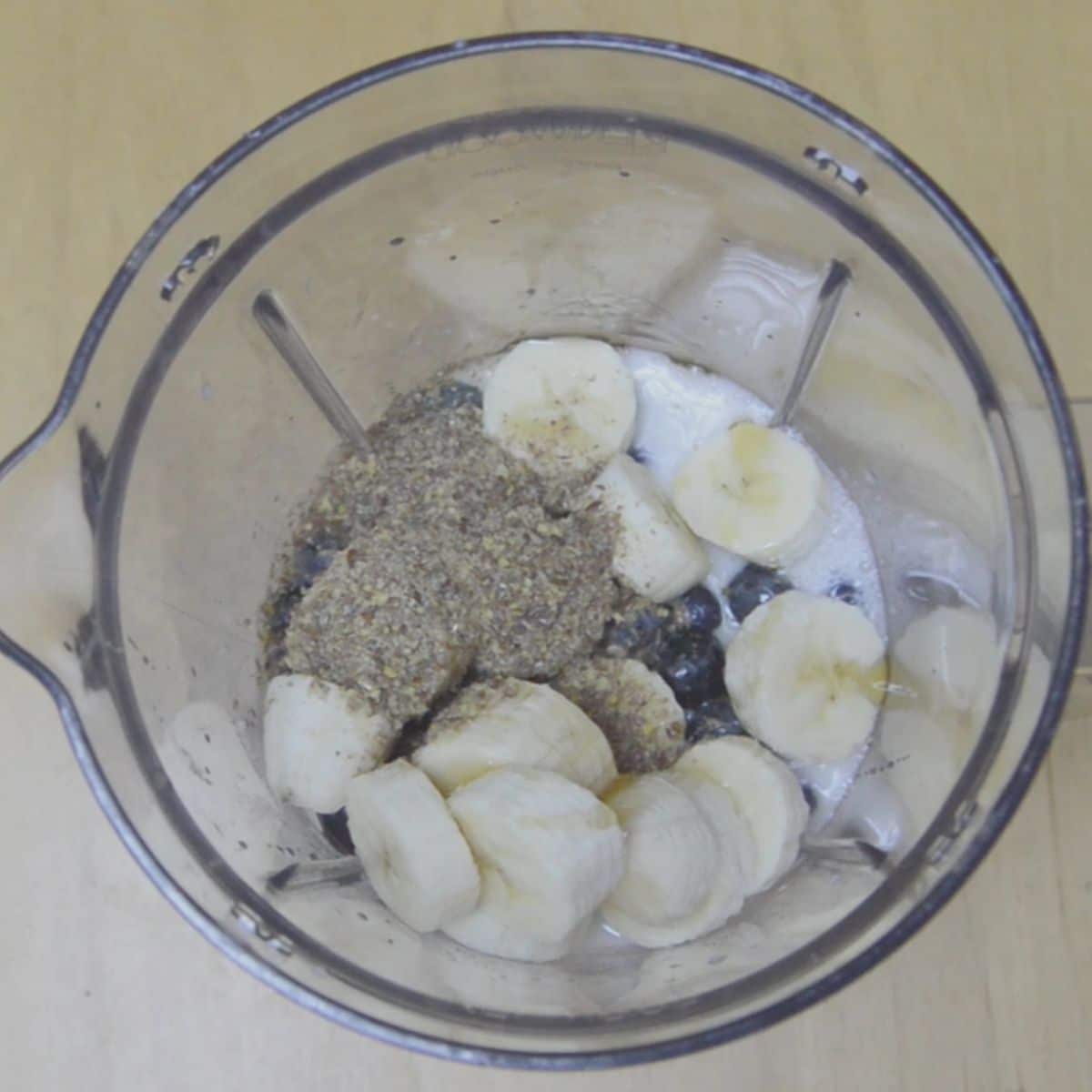 berries, banana, flaxmeal and milk inside the blender.