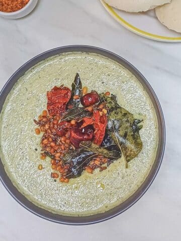 coconut coriander chutney in a bowl with tadka placed on a marble.
