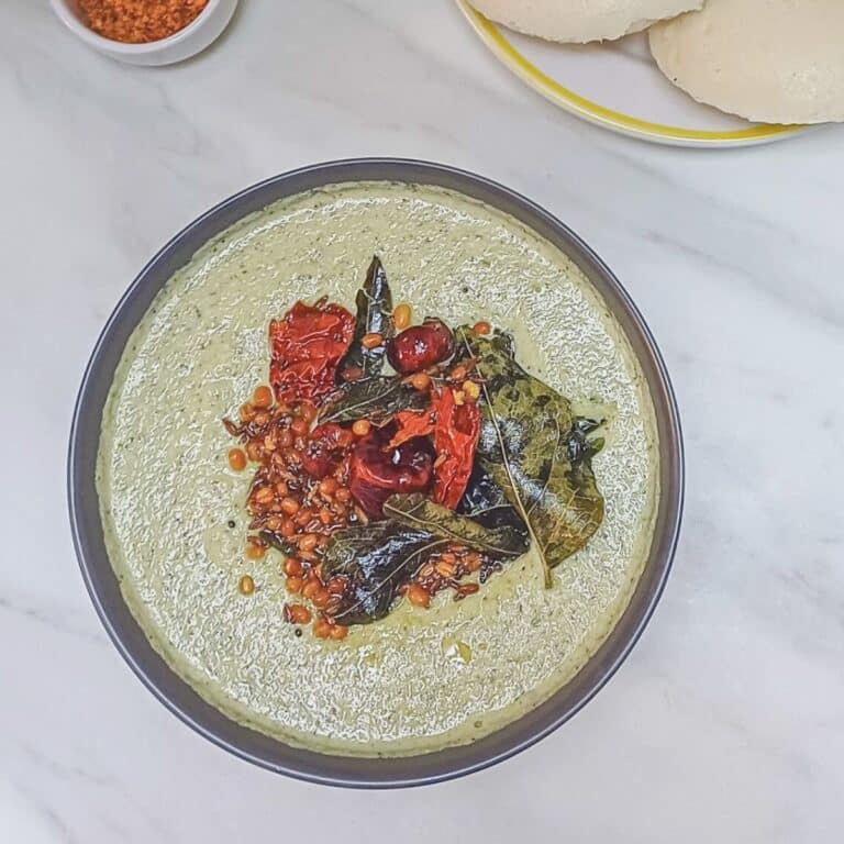 coconut coriander chutney in a bowl with tadka placed on a marble.