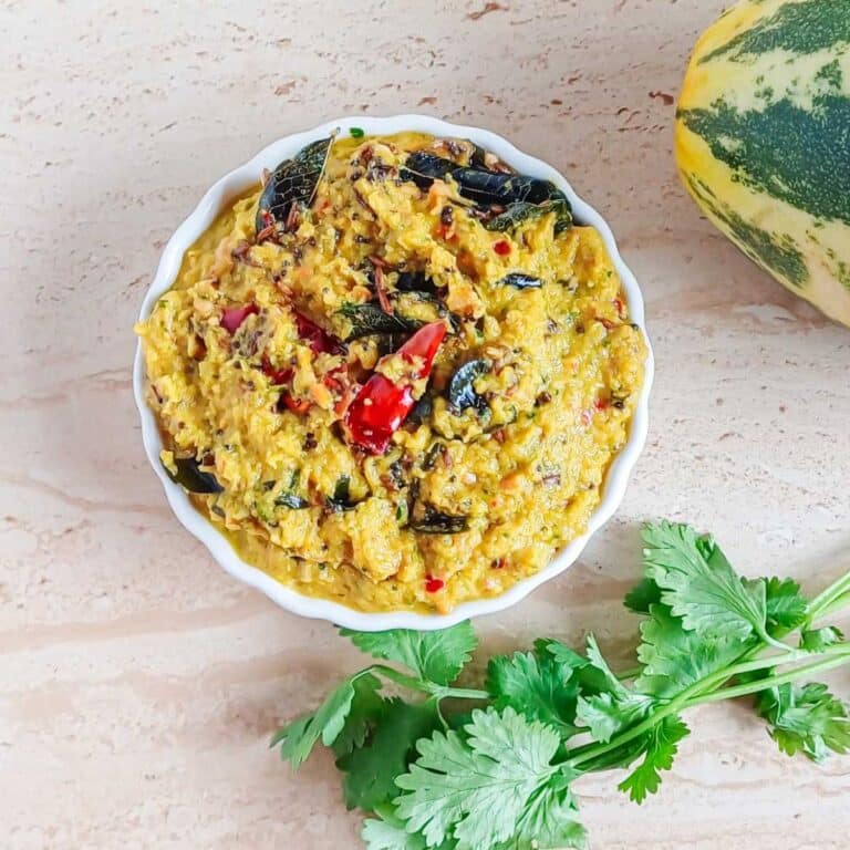 bowl of doskaya pachadi placed on a granite along with a bunch of coriander leaves and cucumber.