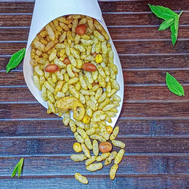 mint murmura chivda in a paper cone placed on brown mat.