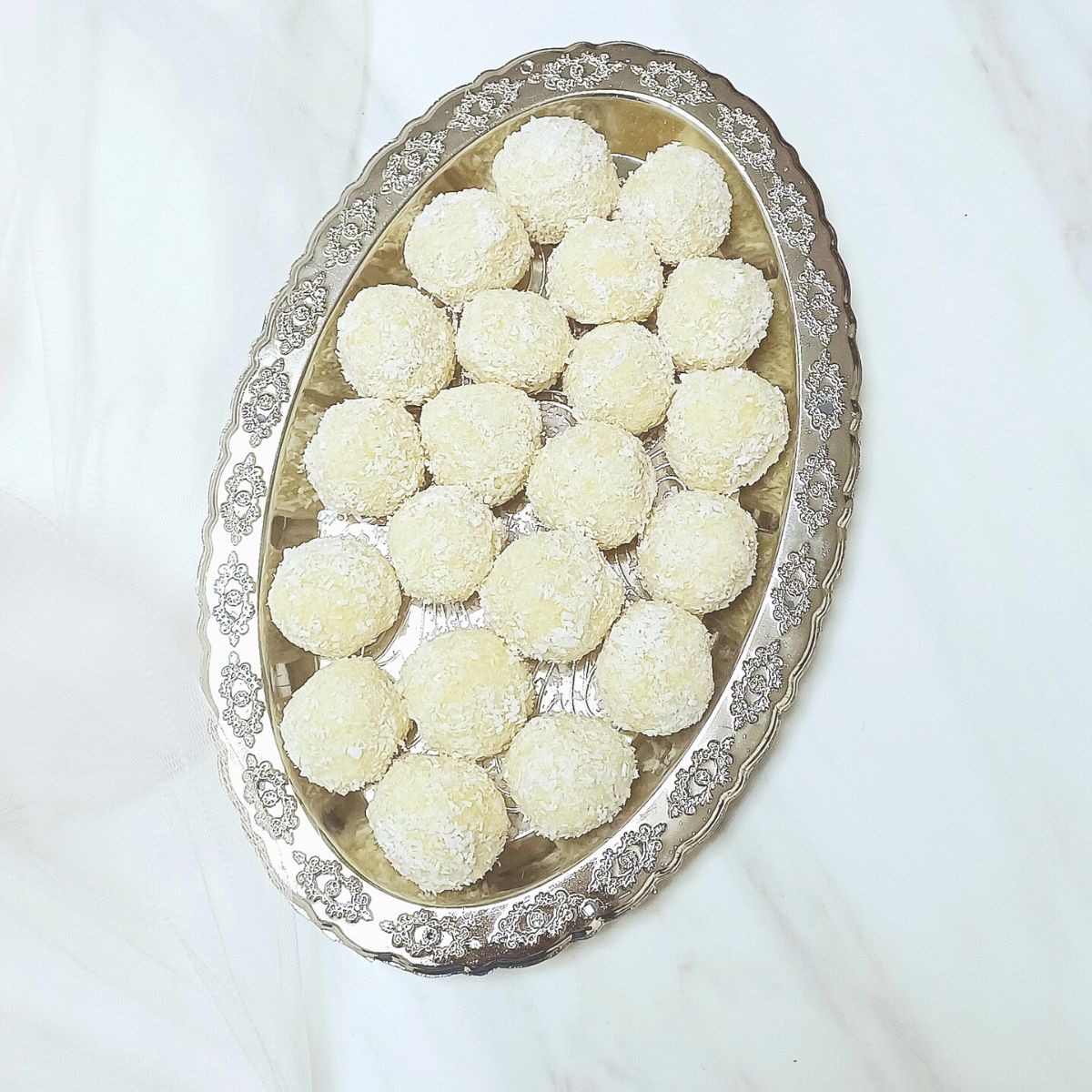 silver plate filled with almond coconut balls placed on a marble.