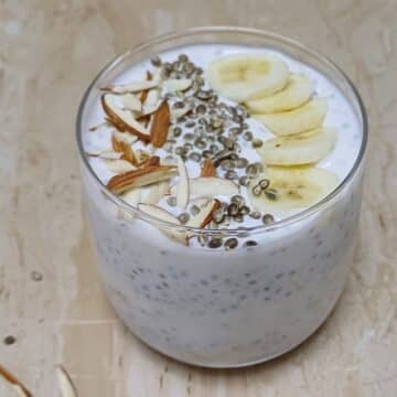 glass of banana chia seed pudding with almonds, hemp seeds and banana topping.