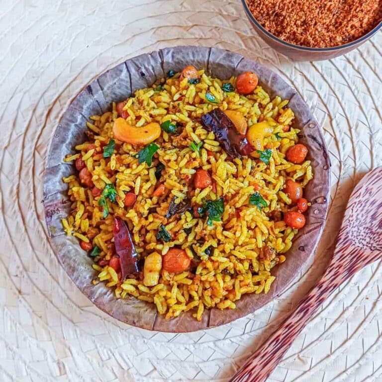 puliyogare in a bowl placed on wooden mat with a wooden spoon.