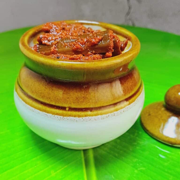 drumstick pickle in a ceramic pot placed on banana leaf.