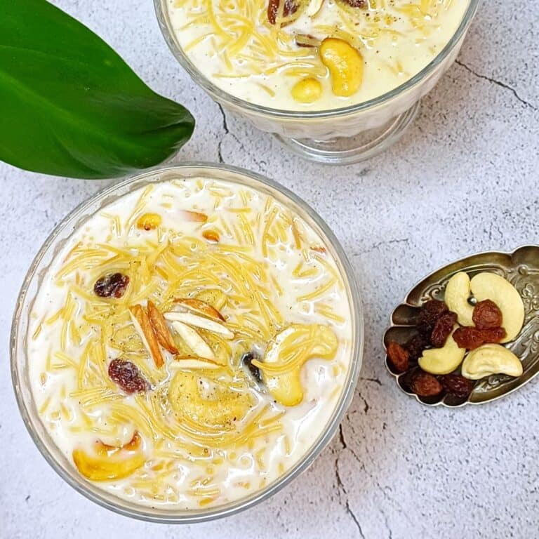 two bowls of semiya payasam placed on tile with a spoonful of cashews and raisins.