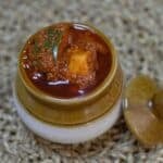 avakaya in a ceramic pot placed on placemat.