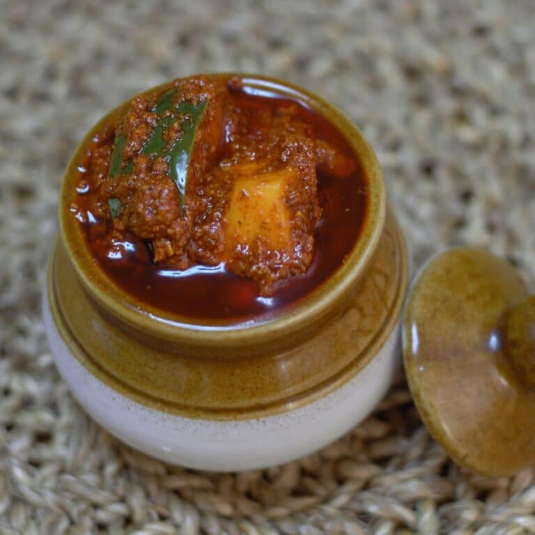 avakaya in a ceramic pot placed on placemat.