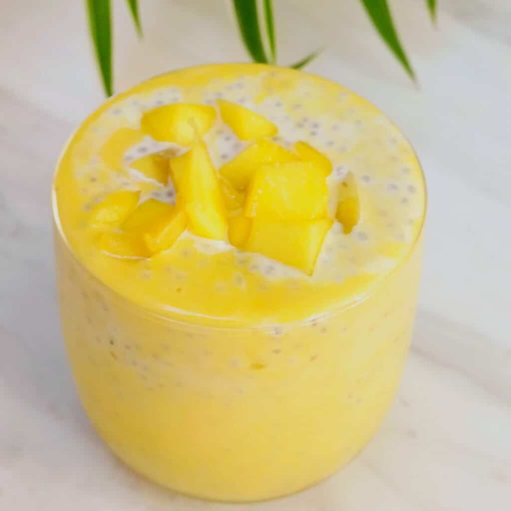 mango chia pudding with fresh mango toppings placed on white marble.