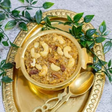 instant pot whole wheat payasam in a golden bowl placed on golden oval plate and spoons.