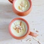 badam kheer in 2 clay glasses garnished with slices almonds.