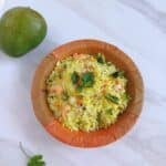 raw mango rice in a brown rice placed on a marble along with a raw mango.