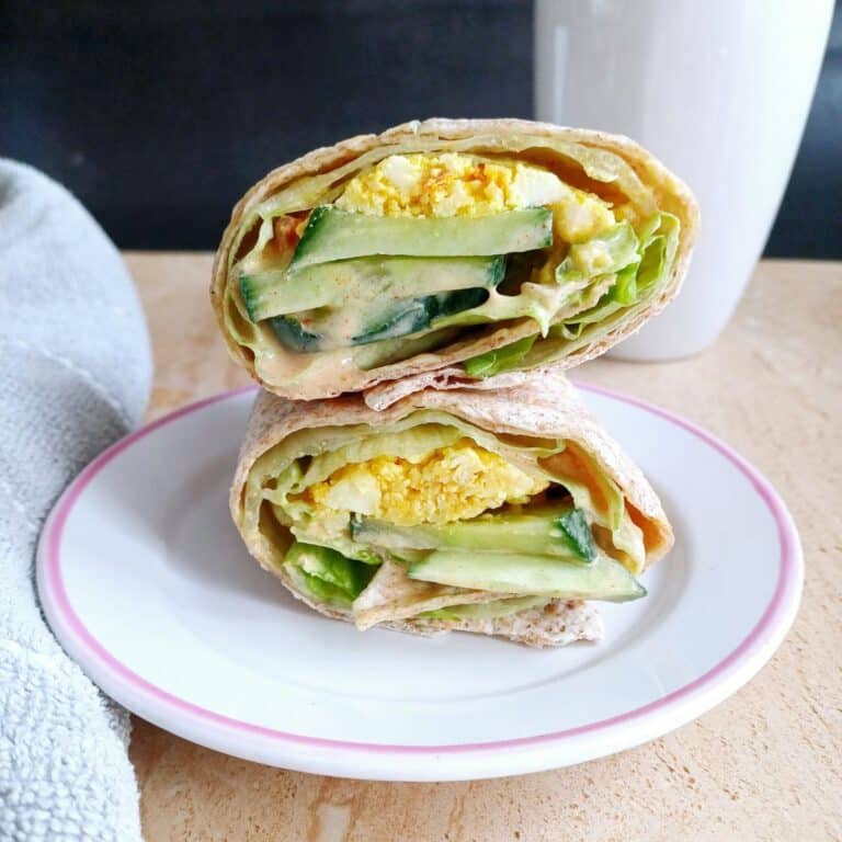spicy tortilla paneer wraps in a plate placed on tile along with a mug.