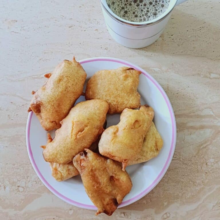plate of banana bajji placed on tile along with a cup of coffee.