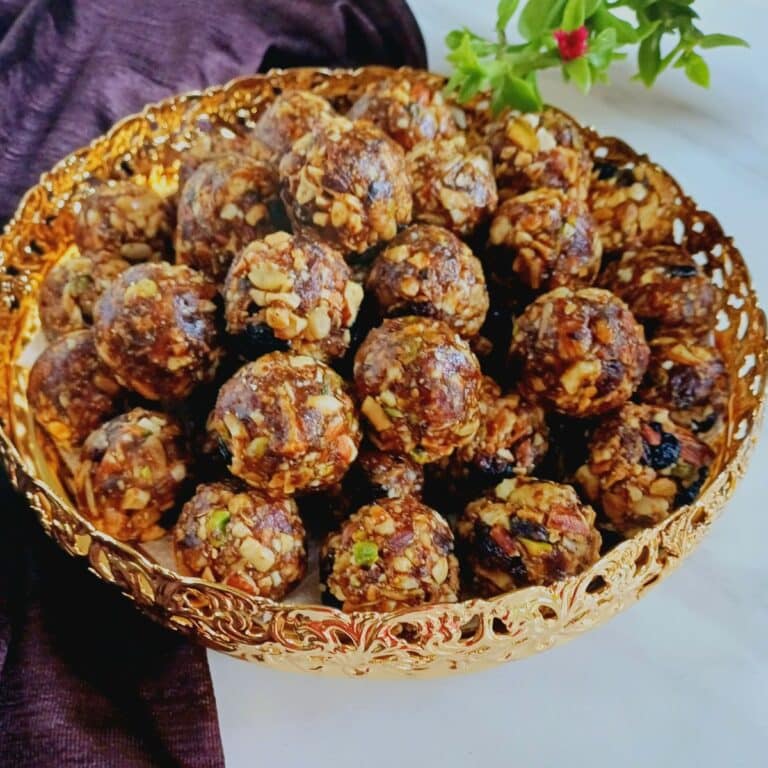 plate filled with dry fruit laddus placed on white marble.