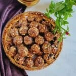 nut and dry fruit laddus in a basket placed on marble with a cloth next to it.