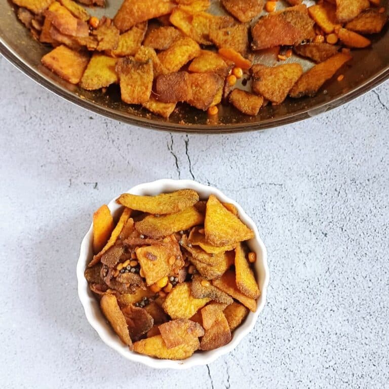 white bowl of elephant yam fry placed on tile along with a steel pan of suran fry.