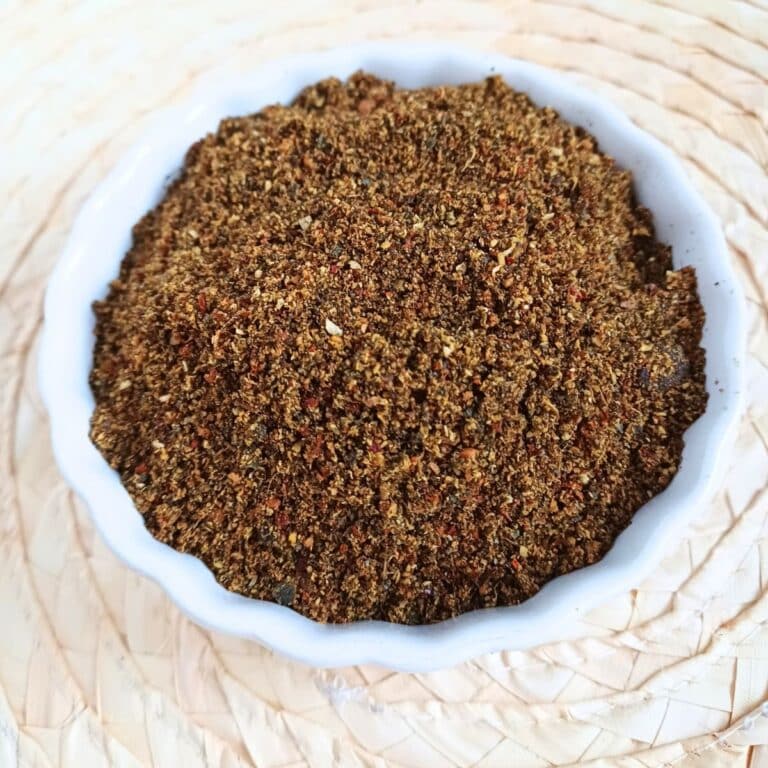 white bowl of karivepaku podi placed on wooden placemat.