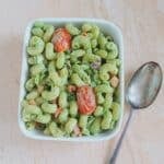 basil vegetable pasta salad in a square bowl placed on a tile along with a spoon.