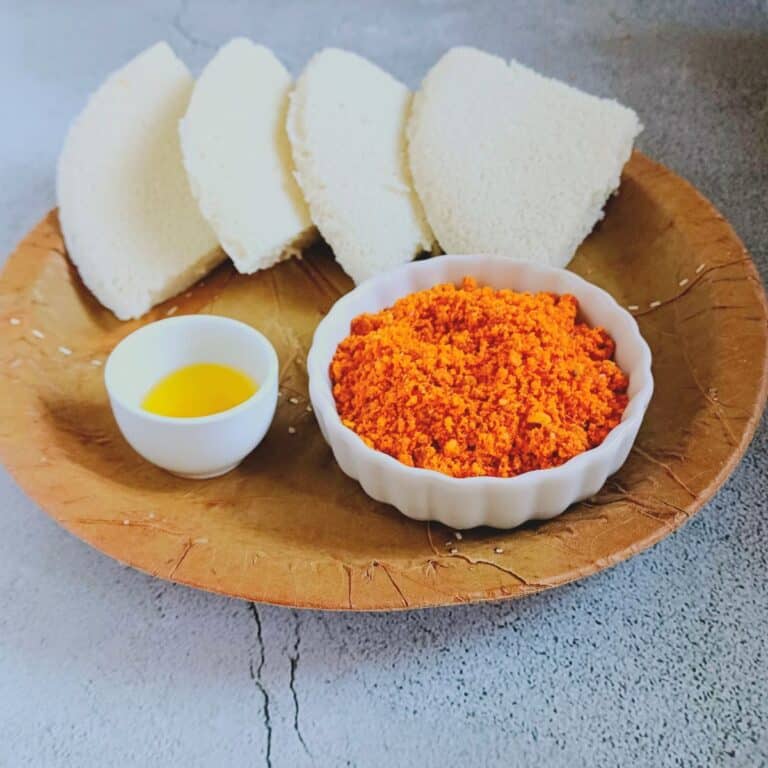palli podi with idli and a bowl of ghee placed in a eco friendly green leaf plate.