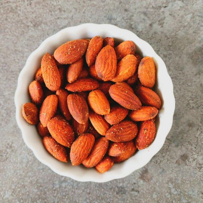 white bowl of spicy roast almonds placed on granite.