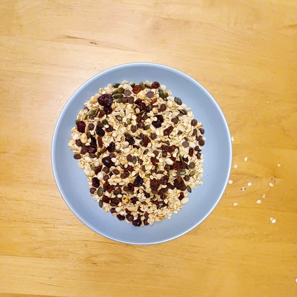trail mix in blue bowl placed on wooden table.