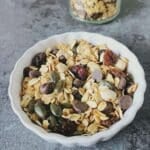 white bowl of healthy trail mix placed on black tile.