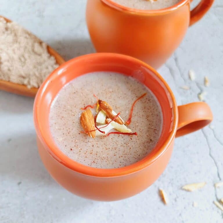 ragi malt in earthen glasses with almond and saffron toppings.