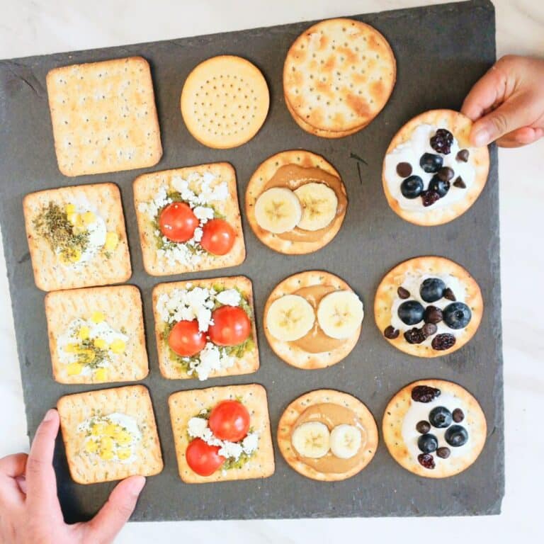 blueberry cracker canapes, pesto feta cracker canapes, peanut butter banana cracker canapes and corn cheese cracker canapes on black slate.