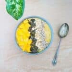 bowl of mango oatmeal breakfast placed on granite along with a spoon.