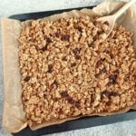baked banana granola on lined baking tray with a wooden spoon.