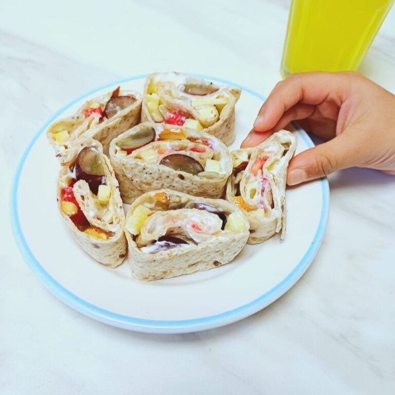 child holding tortilla fruit pinwheels from a plate.
