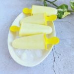 pineapple popsicles on top of ice cubes on a white plate.