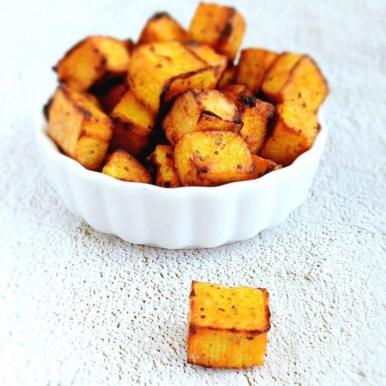 white bowl of spicy baked tofu placed on blue backdrop.