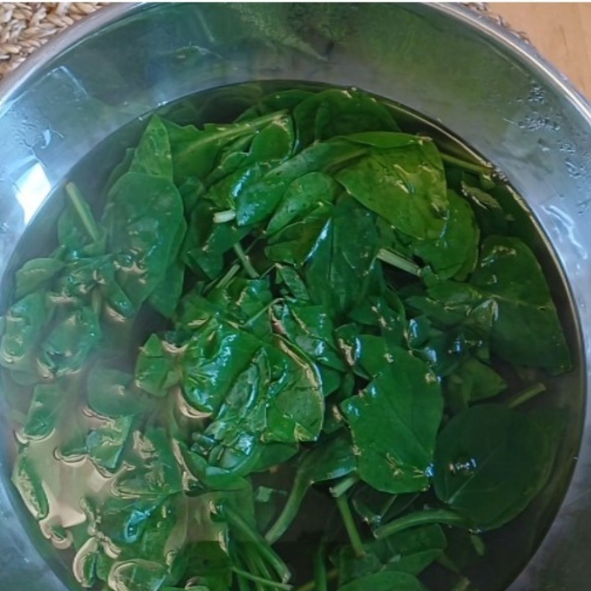 blanched spinach leaves in a steel bowl.