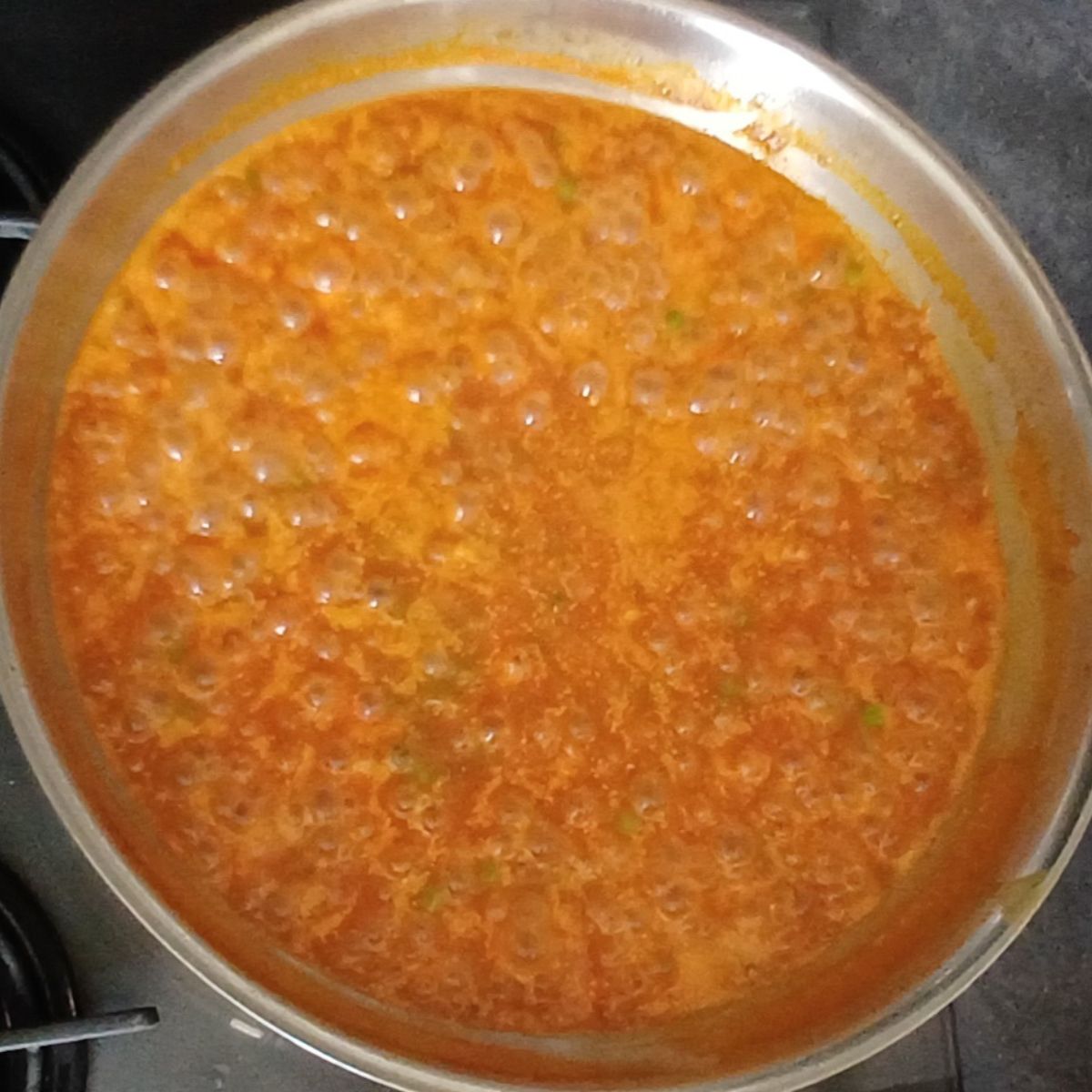 simmering coconut milk pasta sauce in a steel pan.
