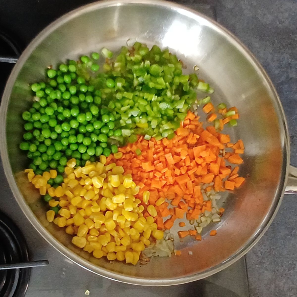 wide steel pan with colourful vegetables on stove top.