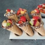 fresh fruits filled in a chocolate coated cones placed inside a cone tray