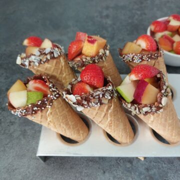 fresh fruits filled in a chocolate coated cones placed inside a cone tray