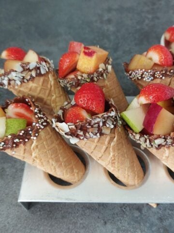 fresh fruits filled in a chocolate coated cones placed inside a cone tray